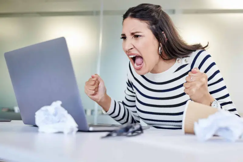 Wütende Frau schreit vor Laptop, frustriert über Probleme im **bad neighbourhood**.